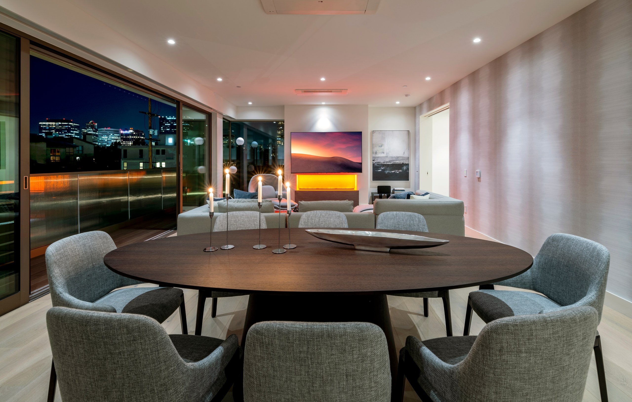Open-plan living and dining framed by a sunset skyline at Lumiere at Malcolm