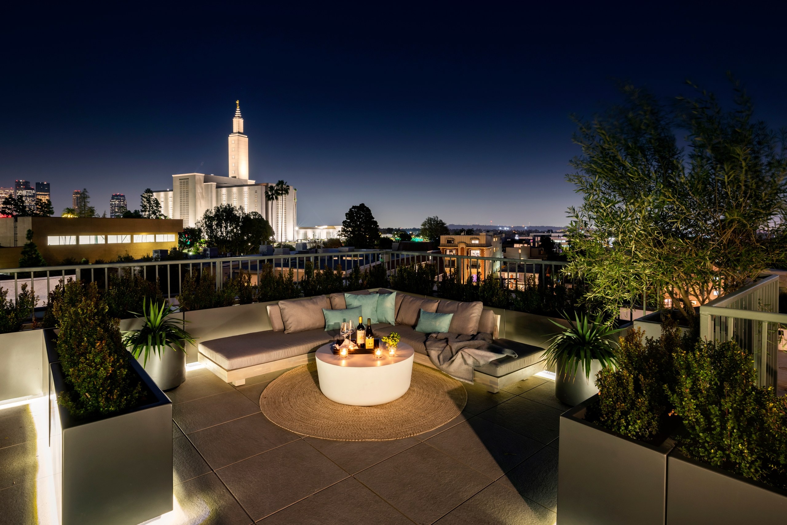 Rooftop lounge with a fire feature at dusk overlooking the Los Angeles skyline at Lumiere at Malcolm